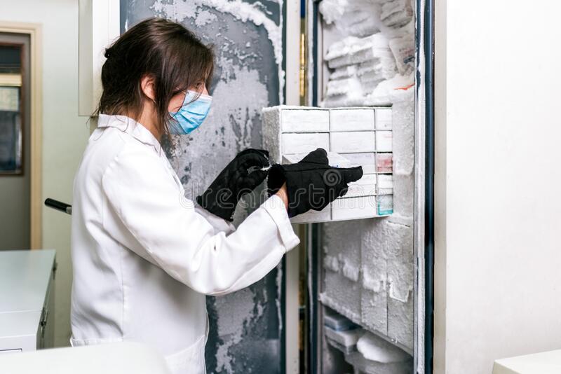 Cold-Storage-inhouse-female-scientist-saving-vaccines-laboratory-stock-photo-wearing-face-mask-using-freezer